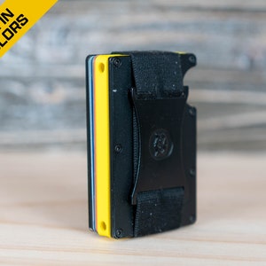 May include: A black metal wallet with a yellow, blue, and red card holder insert. The wallet has a black elastic band with a metal buckle.