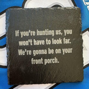 May include: Square black slate coaster with a rough edge. The coaster has white text that reads: "If you're hunting us, you won't have to look far. We're gonna be on your front porch."