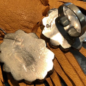 May include: A silver pendant and ring set with a floral design. The pendant is attached to a silver chain and the ring is a band with a floral design.