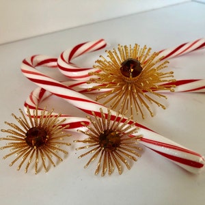 May include: Four red and white candy canes with gold and amber starburst ornaments.
