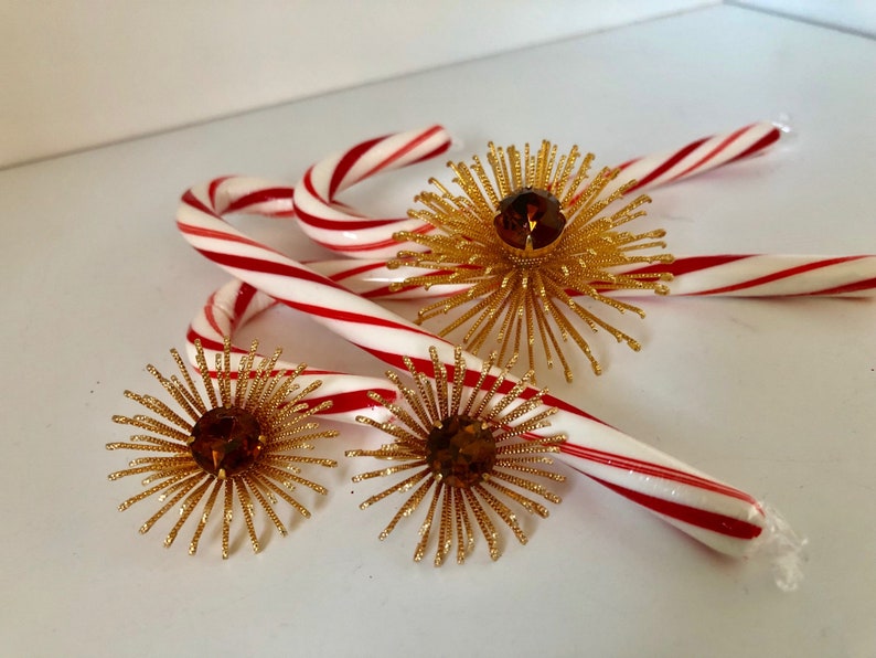May include: Four red and white candy canes with gold and amber starburst ornaments.
