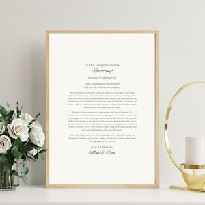 Puede incluir: Impresión enmarcada con un marco dorado. La impresión presenta un poema con el texto "To Our Daughter-in-Law, Brittany on your Wedding Day." El texto está en negro sobre un fondo blanco.