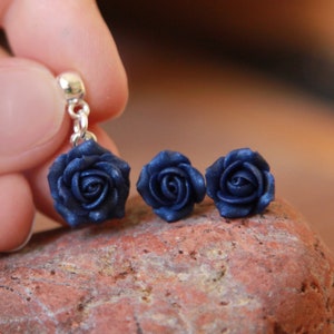 May include: A set of three navy blue rose earrings. The earrings are made of polymer clay and have a silver hook.