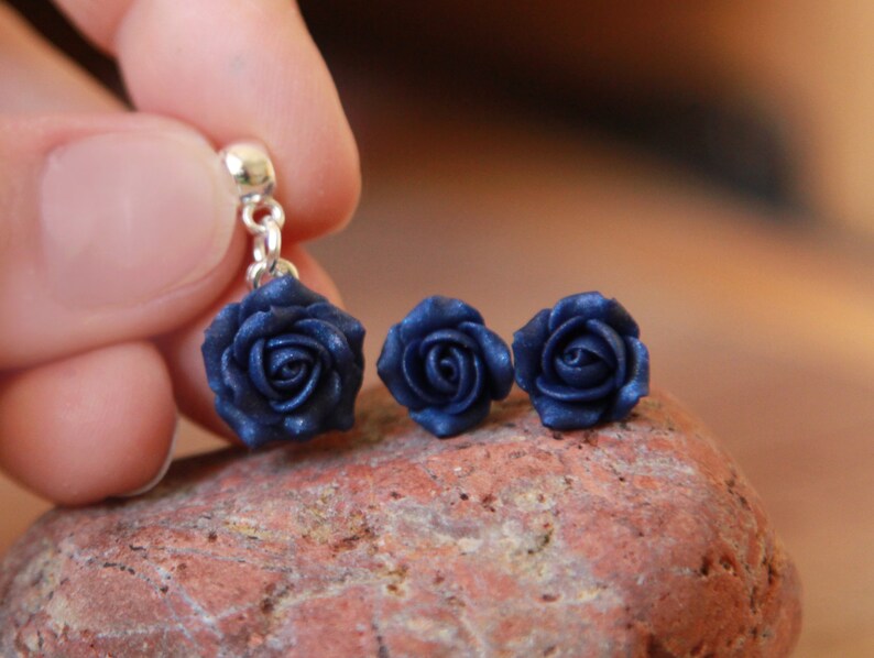 May include: A set of three navy blue rose earrings. The earrings are made of polymer clay and have a silver hook.