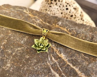 May include: A green velvet choker necklace with a gold-tone pendant featuring a succulent design.