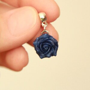 May include: A dark blue rose charm with a silver bail. The rose is made of polymer clay and has a shiny finish.