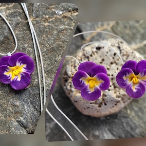 May include: A set of purple and yellow flower earrings and a matching necklace. The earrings are small and the necklace has a silver chain.