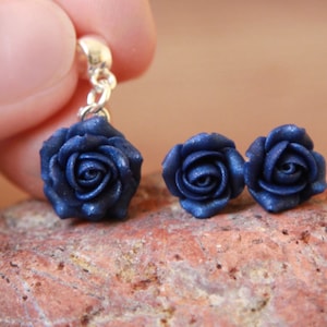 May include: A pair of blue rose earrings with a single blue rose charm on a silver chain.