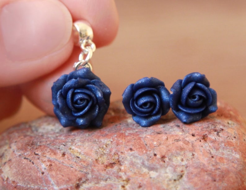 May include: A pair of blue rose earrings with a single blue rose charm on a silver chain.