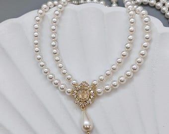 May include: A double strand pearl necklace with a gold pendant featuring a clear crystal and a single pearl drop.