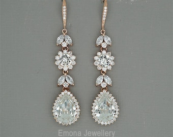 Puede incluir: Pendientes colgantes en tono oro rosa con cristales transparentes. Cada pendiente presenta un cristal en forma de lágrima, un diseño floral y detalles en forma de hoja. Marca: Emona Jewellery.