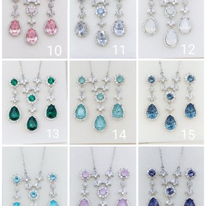 Puede incluir: Un conjunto de 18 juegos de collar y aretes de tono plateado con acentos de cristal de varios colores. Los conjuntos presentan un colgante en forma de l&aacute;grima con un centro de cristal y un acento de cristal m&aacute;s peque&ntilde;o arriba. Los aretes son en forma de l&aacute;grima con un centro de cristal.