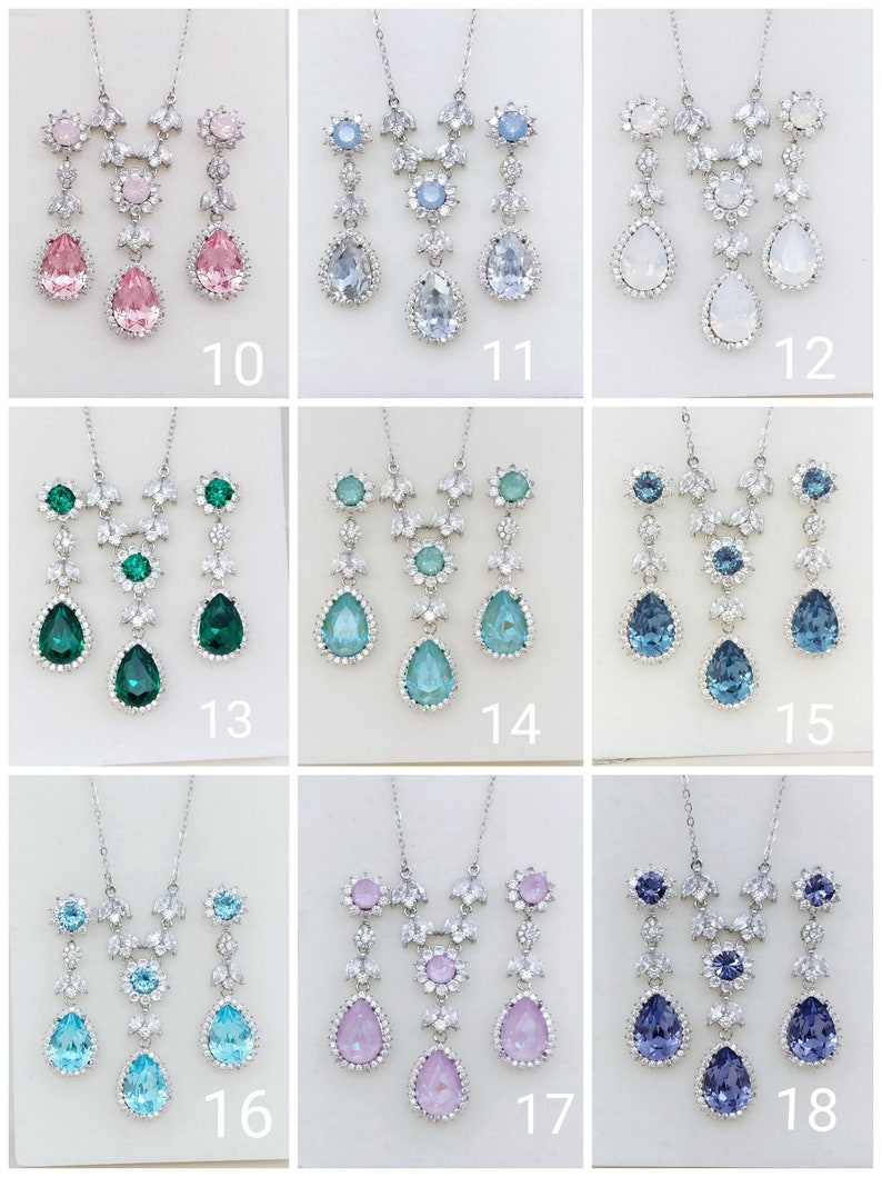 Puede incluir: Un conjunto de 18 juegos de collar y aretes de tono plateado con acentos de cristal de varios colores. Los conjuntos presentan un colgante en forma de l&aacute;grima con un centro de cristal y un acento de cristal m&aacute;s peque&ntilde;o arriba. Los aretes son en forma de l&aacute;grima con un centro de cristal.