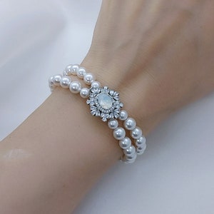 May include: A double strand pearl bracelet with a silver and clear rhinestone flower accent.