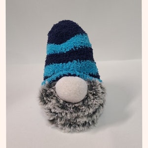 May include: A blue and turquoise striped gnome hat with a white face and a gray and white fur beard.
