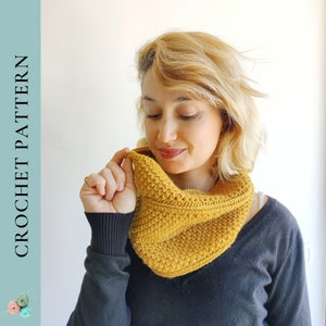 May include: A close-up of a crocheted cowl in a mustard yellow color. The cowl is worn by a person with blonde hair. The cowl is made with a simple stitch pattern.