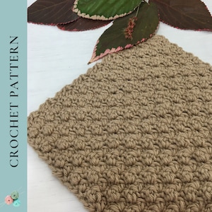 May include: A close-up of a crocheted fabric in a light brown color. The fabric has a textured, bumpy surface. The fabric is on a white surface.