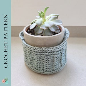 May include: A light green crochet plant pot cover with a potted succulent. The cover has a textured stitch pattern and two small handles. The text "CROCHET PATTERN" is on the left side of the image.