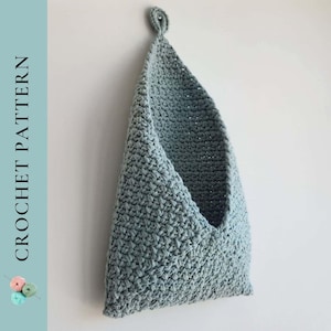 Puede incluir: Una bolsa de almacenamiento colgante de crochet azul claro con un lazo en la parte superior.