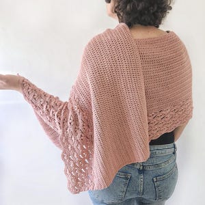 K&ouml;nnte beinhalten: Ein altrosa H&auml;kelschal mit einem einzigartigen Design. Der Schal hat ein strukturiertes Muster an den &Auml;rmeln und Kanten und einen einfachen Stich auf der R&uuml;ckseite. Das Model tr&auml;gt den Schal mit einer blauen Jeans.