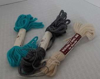 May include: Three skeins of embroidery floss, one turquoise, one gray, and one cream. The skeins are labeled "100% Virgin Wool" and "Persian Needlepoint & Crewel Wool by Bucilla".