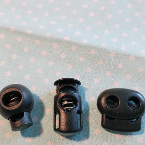 May include: Three black plastic toggle clasps. One is round with a spring inside. One is rectangular with a spring inside. One is oval with two holes.