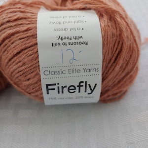 May include: A ball of terracotta colored yarn labeled "Firefly" by Classic Elite Yarns. The label also states "Reasons to knit with Firefly: a bit dressy, light and flowy, a hint of shine" and "75% viscose, 25% linen".