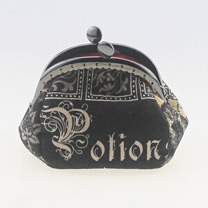 May include: A black fabric coin purse with a silver clasp. The purse has a gold and black floral pattern and the word "Potion" printed on the front.