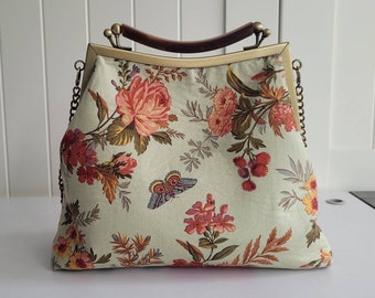 Spring floral print shoulder bag or handbag with metal frame kiss lock opening and mock tortoise shell top handle and a metal chain.