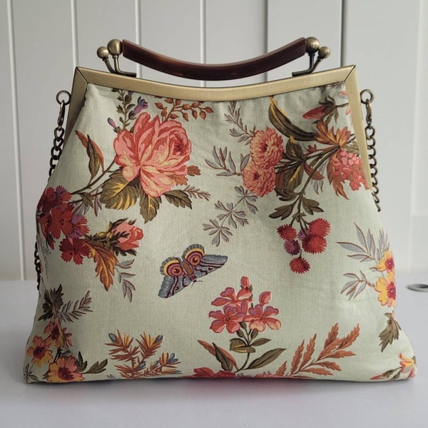 Spring floral print shoulder bag or handbag with metal frame kiss lock opening and mock tortoise shell top handle and a metal chain.