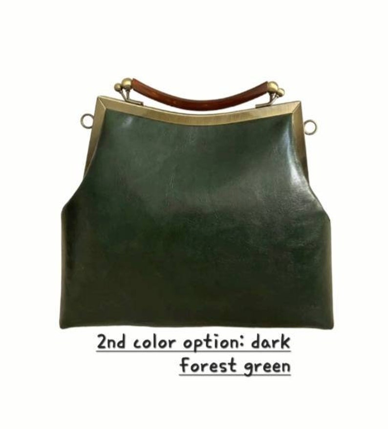 May include: Dark forest green handbag with a curved wooden handle and brass-colored metal frame. The bag has a structured shape and a clasp closure. The text at the bottom reads "2nd color option: dark forest green."