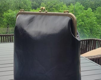 Vegan leather lap top carrying bag with kiss lock metal frame opening.  Convertible large sized backpack or shoulder bag or school bag