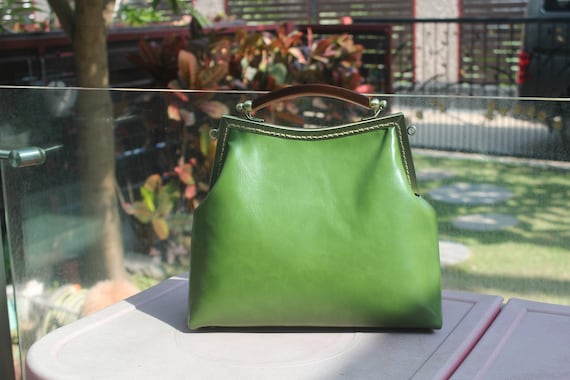 Vegan leather bag with metal frame kiss lock opening and mock tortoise shell top handle