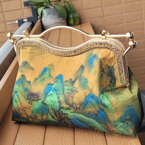 Oriental scenery print handbag or crossbody with metal frame kiss lock clasp handle and a metal chain.