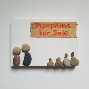 May include: A stone art piece depicting a family of five standing in front of a sign that reads "Pumpkins For Sale".