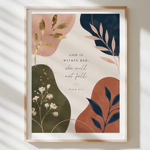 May include: A framed wall art print featuring abstract organic shapes in muted tones of pink, dark green, navy blue, and terracotta. The centre displays the text "GOD IS WITHIN HER. she will not fall. PSALM 46:5" with gold-coloured botanical illustrations.