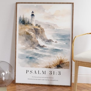 May include: A framed watercolour print depicting a coastal landscape with a lighthouse, waves, and the text "PSALM 31:3". The artwork is in a wooden frame and displayed indoors.