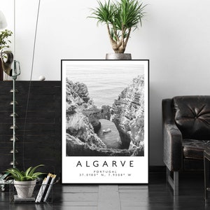 May include: Black and white photograph of a rocky coastline with a small boat in the water. The text "ALGARVE" is printed below the image, along with the coordinates "37.0180&deg; N, 7.9308&deg; W".
