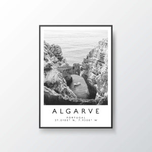 May include: Black and white photograph of a rocky archway over a body of water. A small boat is visible in the water below the archway. The text "ALGARVE PORTUGAL 37.0180&deg; N. 7.9308&deg; W" is printed below the image.