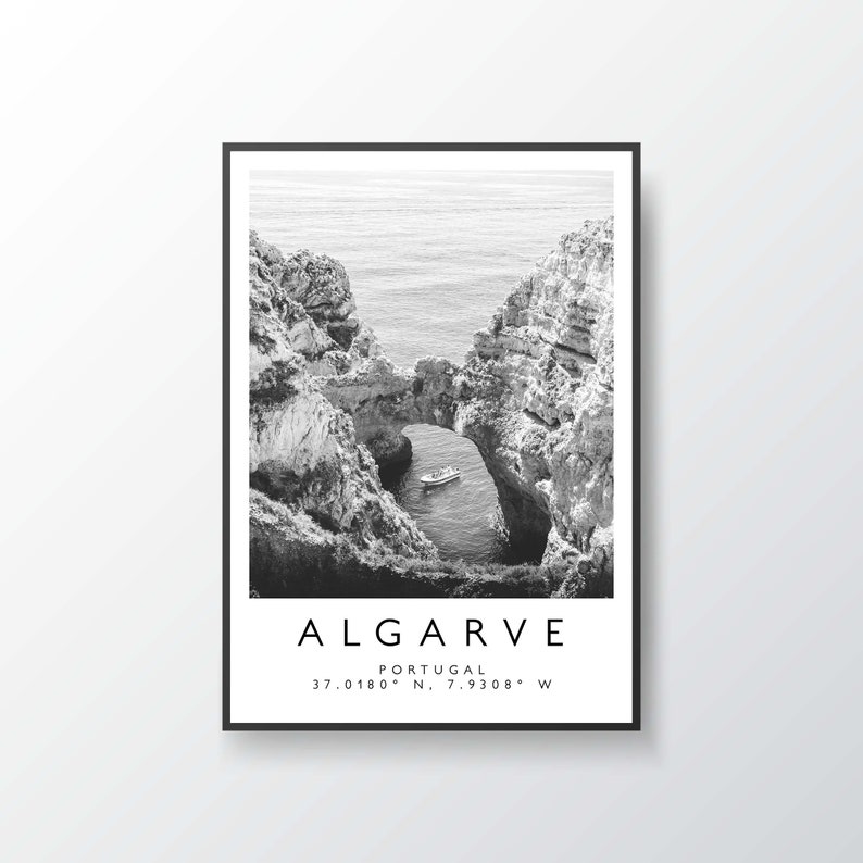 May include: Black and white photograph of a rocky archway over a body of water. A small boat is visible in the water below the archway. The text "ALGARVE PORTUGAL 37.0180&deg; N. 7.9308&deg; W" is printed below the image.