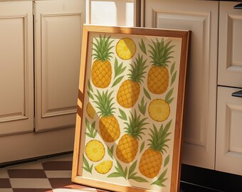 May include: A framed art print featuring a repeating pattern of ripe pineapples and pineapple slices on a cream-colored background. The pineapples are yellow with green leafy tops, and the frame is a light brown color. The artwork is leaning against a white cabinet.