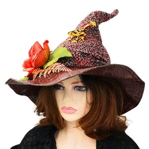 May include: A red and black witch hat with a brown leather brim, a yellow frog figurine, and a red rose with green leaves.