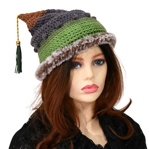 May include: A unique, handmade crochet hat with a faux fur trim. The hat features a color block design in brown, gray, and green, with a decorative tassel. This stylish hat is perfect for adding a touch of flair to any outfit.