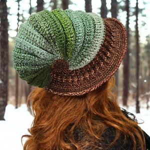 May include: A crocheted hat featuring a spiraling, ribbed design in shades of green, transitioning from light to dark tones. The hat includes a wide, textured brown brim with a metallic sheen, constructed with intricate yarn stitching throughout.