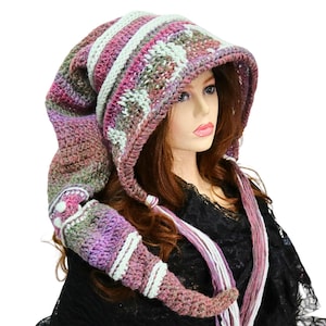 May include: A long, pointed crochet hood featuring a variegated color palette of purple, green, and brown yarn. The hood includes horizontal stripes of light mint green and is finished with long, braided yarn tassels hanging from the front edges.