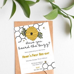 Könnte beinhalten: Eine weiße Einladung mit einer gelben und schwarzen Bienenstock-Illustration. Der Text lautet "Have you heard the buzz? We're celebrating our little honey Henry's First Bee-Day. Samstag, 7. Oktober um 11:00 Uhr. 123 Street Address, City, State 11111. RSVP 123-456-7890."