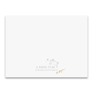 May include: A white card with a gray line drawing of a rabbit jumping with stars. The text "A RISING STAR" and the website address "allakiyama.com/risingstar" are printed in gray. The text "Ai Akiyama" is written in gold cursive.