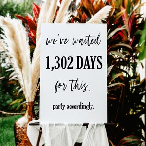 Könnte beinhalten: Ein weißes Schild mit schwarzem Text, auf dem steht "We've waited 1,302 DAYS for this. Party accordingly."