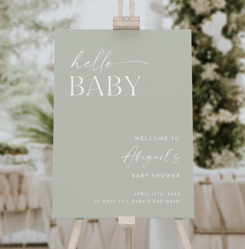 May include: A sage green welcome sign with white text that reads "hello BABY", "WELCOME TO Abigail's BABY SHOWER", "APRIL 15TH, 20XX", and "35 DAYS TILL BABY'S DUE DATE!"
