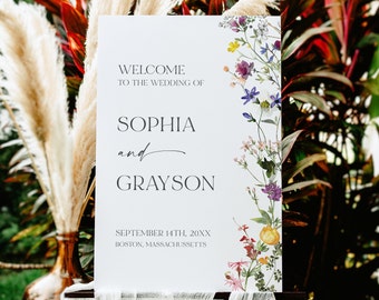 May include: White wedding welcome sign with floral border. The sign reads "Welcome to the wedding of Sophia and Grayson, September 14th, 20XX, Boston, Massachusetts."